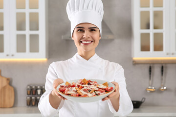 Portrait of professional chef presenting delicious dish in kitchen