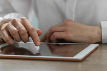 Closeup view of woman using modern tablet at table