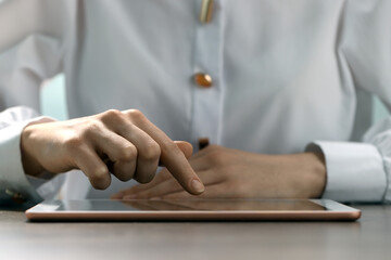 Closeup view of woman using modern tablet at table