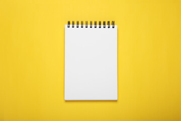 Blank office notebook on yellow background, top view