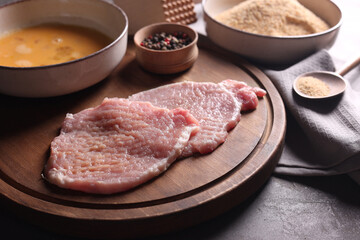 Cooking schnitzel. Raw pork slices and other ingredients on grey table, closeup