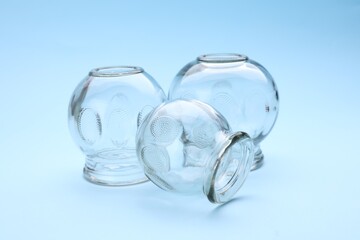 Glass cups on light blue background. Cupping therapy