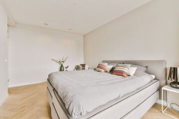 a bedroom with white walls and wood flooring in the room, there is a bed that has pillows on it