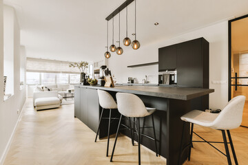 a kitchen and dining area in a modern apartment with white walls, hardwood flooring and black...