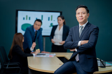 Handsome Asian middle-aged executives business man standing confident in the office in front of his team.