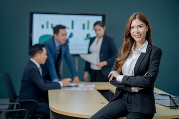 Successful young businesswoman executives and business women are standing confident in the office in front of their team.