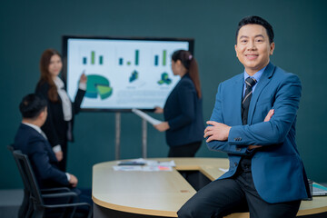 Handsome Asian middle-aged executives business man standing confident in the office in front of his team.
