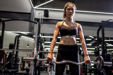 Portrait of a young Asian woman, good-looking, shapely, in a black dress. She's working exercise fitness out in a world-class gym.