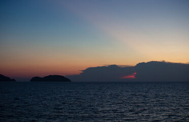 The sky and the sea in the evening near the sun will set. The golden yellow light against the water was a beautiful moment. sometimes saw mountain shadows interspersed