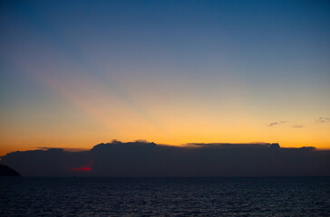 The sky and the sea in the evening near the sun will set. The golden yellow light against the water was a beautiful moment. sometimes saw mountain shadows interspersed