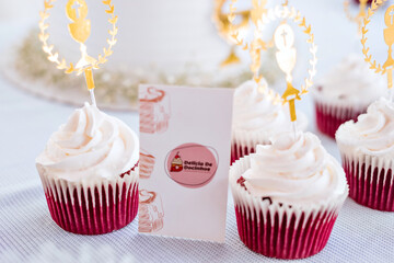 a cake with white frosting and gold accents and red velvet cupcakes