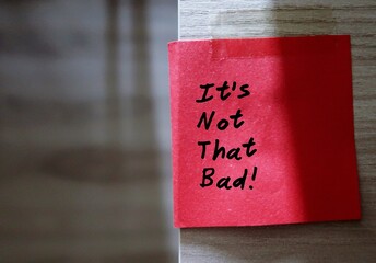 Red sticky note with text written IT'S NOT THAT BAD  - concept of self reminder or a cheer up note...
