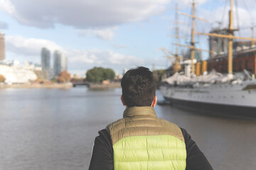 Back view of a tourist posing in front of a boat in Puerto Madero, Buenos Aires, Argentina