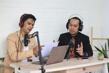 Young radio host giving the question to businessman in suit while recording podcast for online show...