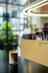 Iced coffee in glass on table in coffee shop blur background.