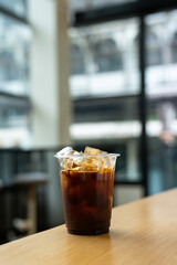 Iced coffee in glass on table in coffee shop blur background.