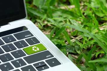 environmental technology concept.green recycle button on a black keyboard on green grass. Recycle...