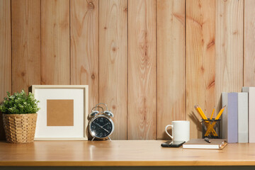 Fototapeta na wymiar Creative workplace with picture frame, clock and plant on white table against wall copy space.