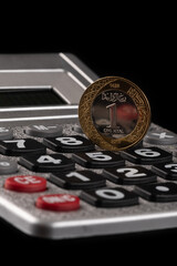 1 riyal coin of the Kingdom of Saudi Arabia and a calculator on a black background