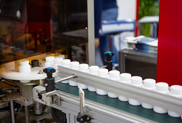 White plastic bottle on capsule filling machine conveyor belt in production line. Pharmaceutical industry	
