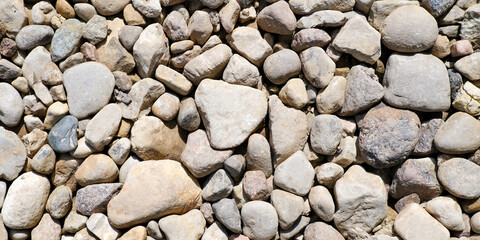 Abstract background with brown and beige dry stones, cobblestones, gravel. Gravel texture or background for design, for banner. Real grunge background texture and small stone. Close up, top view.