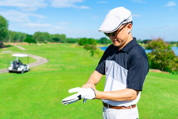 Confidence Asian man golfer wearing sport gloves for golfing on golf course fairway in sunny day. Healthy people enjoy outdoor activity  lifestyle sport golf at country club on summer holiday vacation