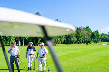 Group of Asian businessman and senior CEO talking together during golfing on golf course. Healthy retired elderly people enjoy outdoor activity lifestyle at country club on summer holiday vacation.