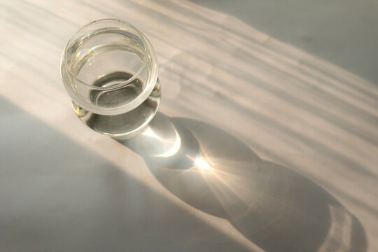 Glass cup on the table with the reflection of sun rays. minimalistic concept