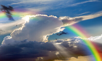 Fototapeta premium Rays of the sun breaking through the stormy sky, forming a marvelous rainbow