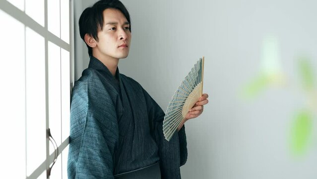 扇子であおぐ和服の男性