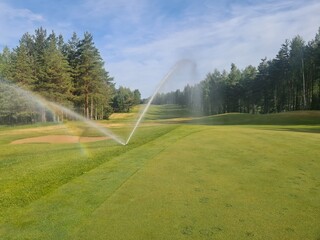Sprinklers watering system working in fairway and sand bunker of green golf course concept