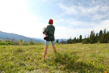 Woman doing yoga on blossom meadow and mountains background. Morning healthy activity.