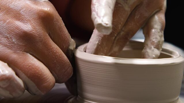 Potter forms a clay product with ceramic tools on a potter's wheel. Pottery workshop. Close-up. Art education, ceramics, clay molding