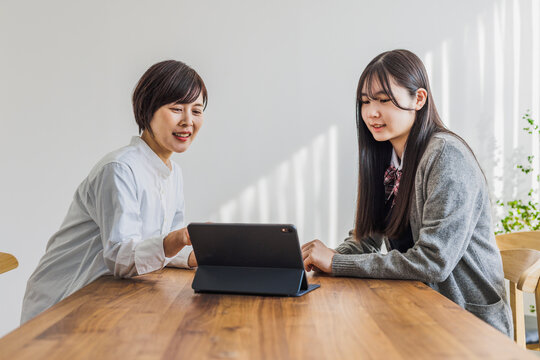 タブレットを見る日本人女性と女子学生