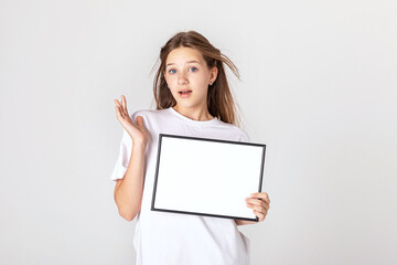 White banner .Teenager girl hold white blank paper. Young surprised woman show blank board. Close up female model portrait on white background.