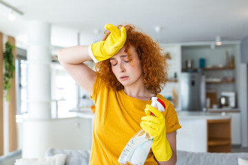 Portrait of young tired woman with rubber gloves resting after cleaning an apartment. Home,...