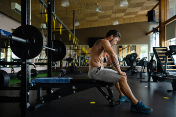 Exhausted man sitting on a bench of a gym