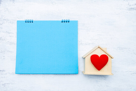 Blank blue card with wooden house model and red heart on white background, buy new hosue, property investment, real estate business