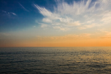 Fototapeta na wymiar beautiful and colorful sunset, warm light and many clouds, sea waves on the sea coast