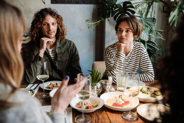 Group of friends talking while dining in restaurant