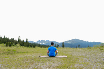 Men in meditation on yoga mat in mountains landscape. Outdoor yoga in mountains