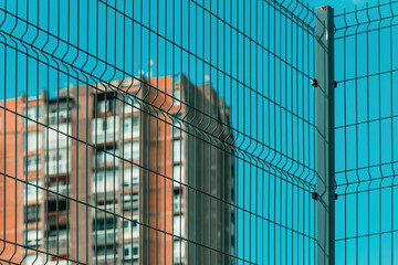 High rise architectural brutalism style apartment building behind metal fence