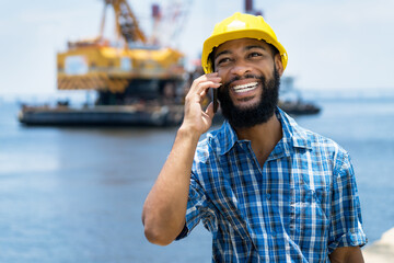 Laughing african american offshore worker talking with boss at phone
