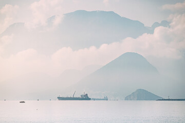 Panoramic seascape view with cargo ship and mountains