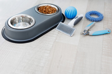 Fototapeta na wymiar Nail clipper, hair comb, food and blue toys on floor with copy space