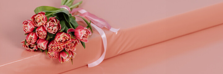 Bouquet of pink tulips on a pink surface. Congratulations on March 8, Women's Day or Mother's Day. Banner for website header design with copy space. Banner for website header design with copy space.