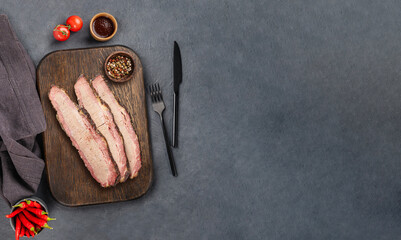 Grilled brisket meat slices with bbq sauce, tomato and pepper  on a dark background. Delicious...