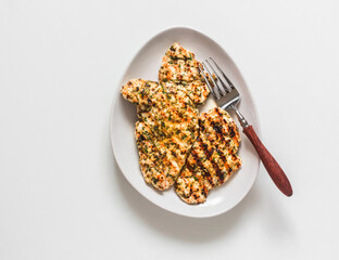 Lime, cilantro, garlic, mustard, olive oil  marinated grilled chicken breast on a light background, top view