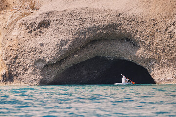 Group of sup boarders enters huge limestone cave on a sea coast