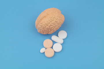 Human brain and medical pills on blue background. Medicine for mental health concept.